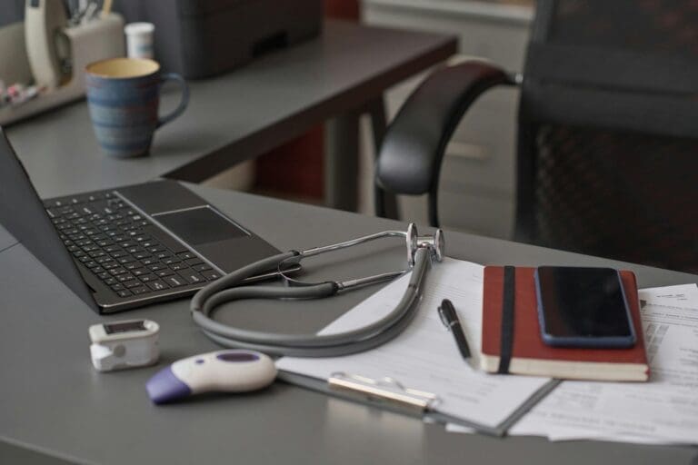 Echipament medical pe un birou cu laptop deschis.